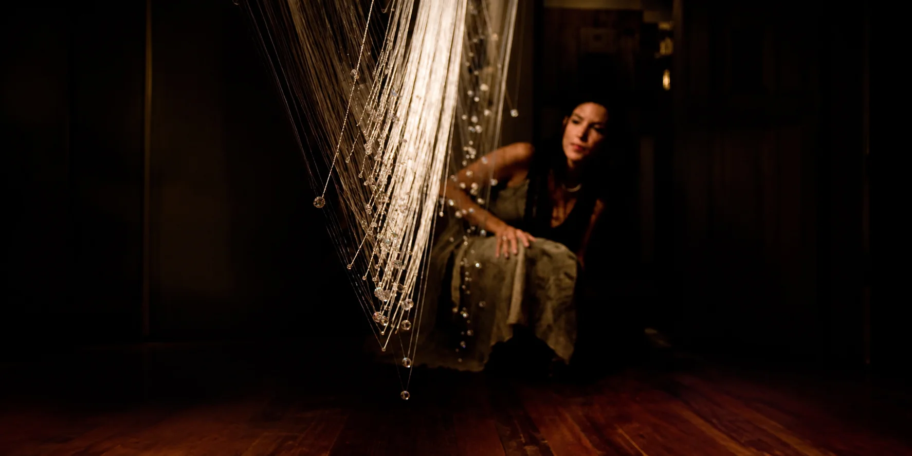 Portrait beside a suspended thread and crystal installation.